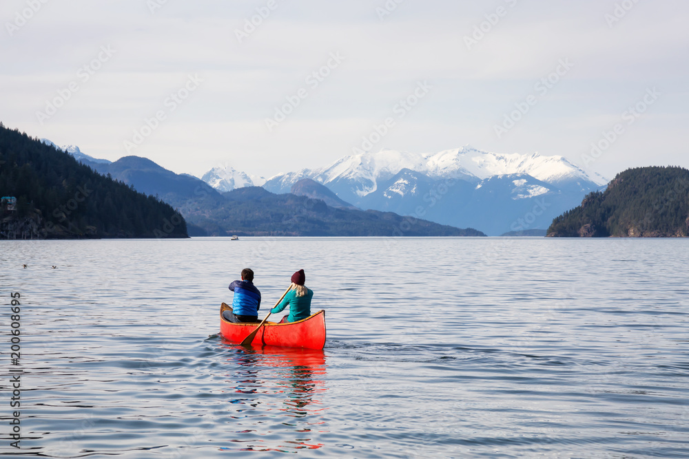 Naklejka premium Couple friends canoeing on a wooden canoe during a sunny day. Taken in Harrison Lake, East of Vancouver, British Columbia, Canada.