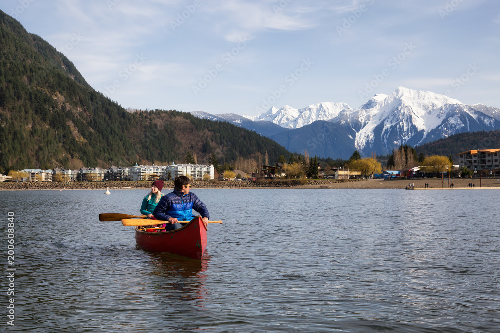 Couple friends canoeing on a wooden canoe during a sunny day. Taken in Harrison Lake, East of Vancouver, British Columbia, Canada.