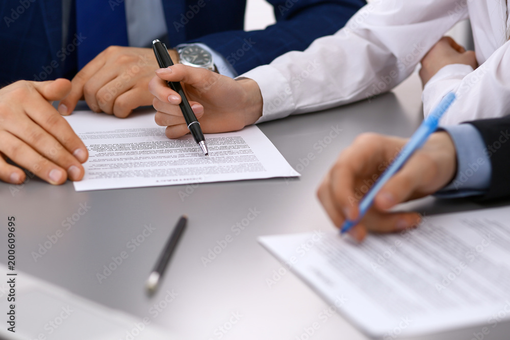 Group of business people and lawyer discussing contract papers sitting at the table, closeup. Businessman is signing document after agreement done Group of business people and lawyer discussing contract papers sitting at the table, closeup. Businessman is signing document after agreement done