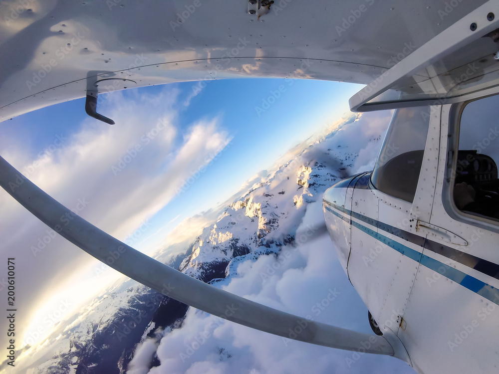 Obraz premium Small airplane flying over the Canadian Mountain Landscape during a vibrant sunset. Taken near Squamish, North of Vancouver, British Columbia, Canada.
