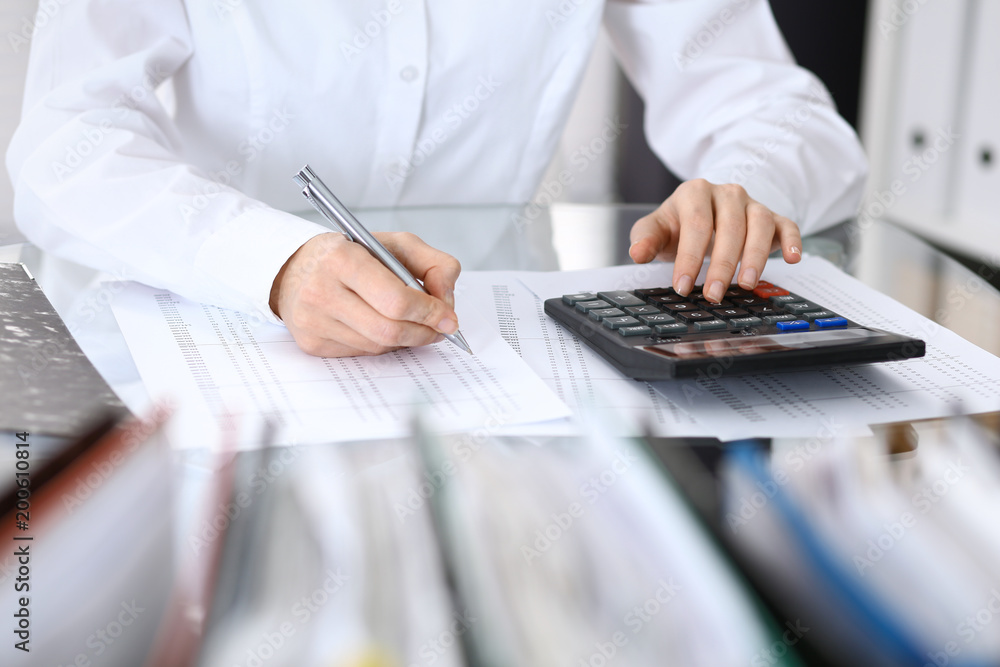 Fototapeta premium Female bookkeeper or financial inspector making report, calculating or checking balance. Internal Revenue Service checking financial document. Audit concept in business