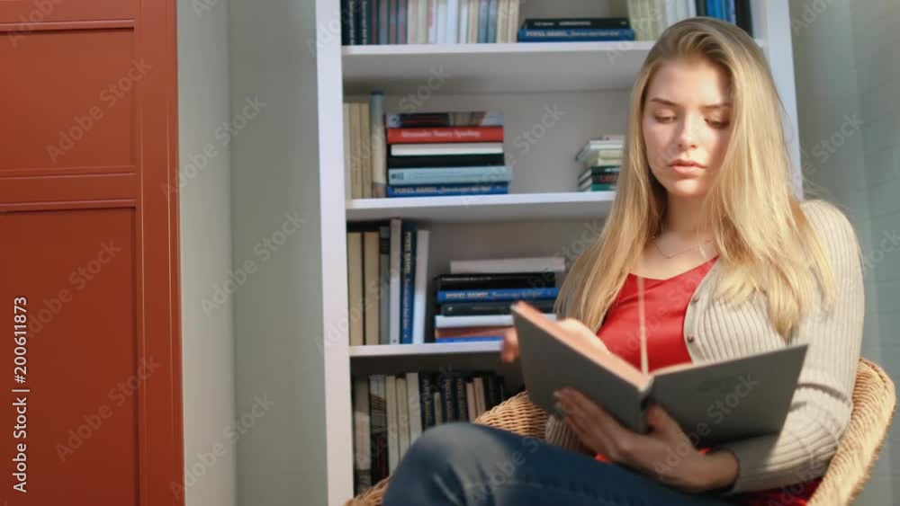 A girl with long hair reads a book indoors. A large shot. A girl with long hair reads a book indoors. A large shot.