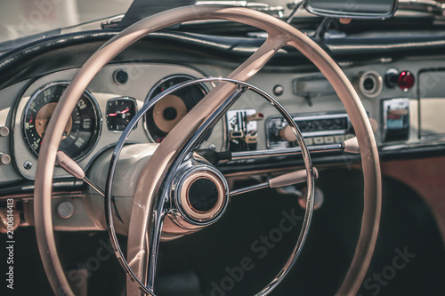 Close-up, detailed photo of the interior, dashboard, steering wheel and speedometer of a classic oldtimer luxury sports car.