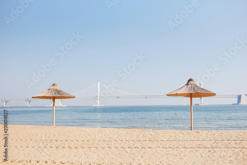 Sand beach. Beach straw umbrellas against the background of the blue sea and the sky.