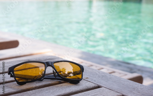 sunglassed on wood table near swimming pool
