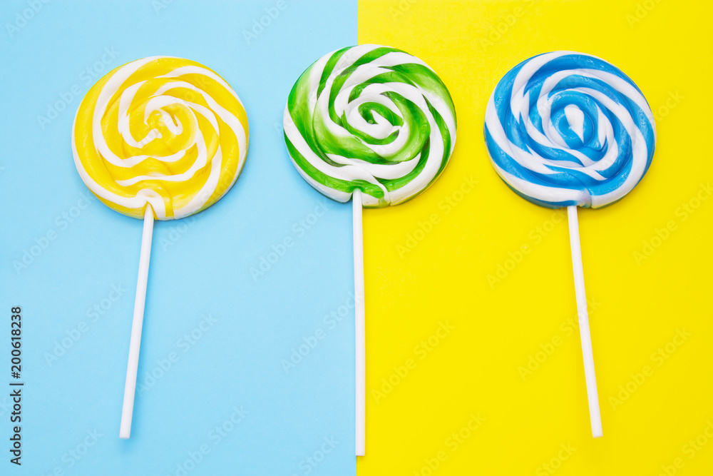 colorful lollipops on yellow and blue background colorful lollipops on yellow and blue background