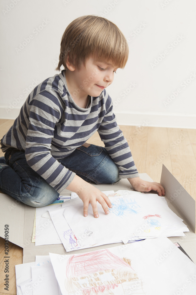 Niño (5 años) revisando en una carpeta sus dibujos. Niño (5 años) revisando en una carpeta sus dibujos.