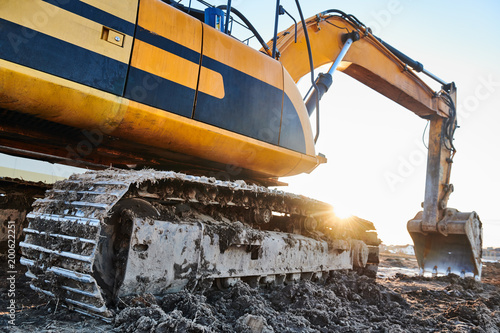 excavation work. Excavator at construction site with sunset photo