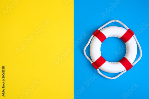 Lifebuoy on a yellow and blue background with blank space for text. Top view travel or vacation concept. Summer background. Flat lay photo, top view.