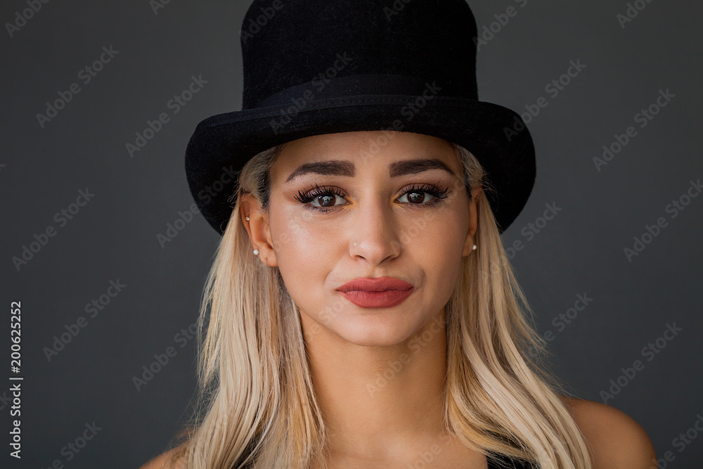Beautiful and lovely woman portrait wearing top hat and looking at camera Beautiful and lovely woman portrait wearing top hat and looking at camera