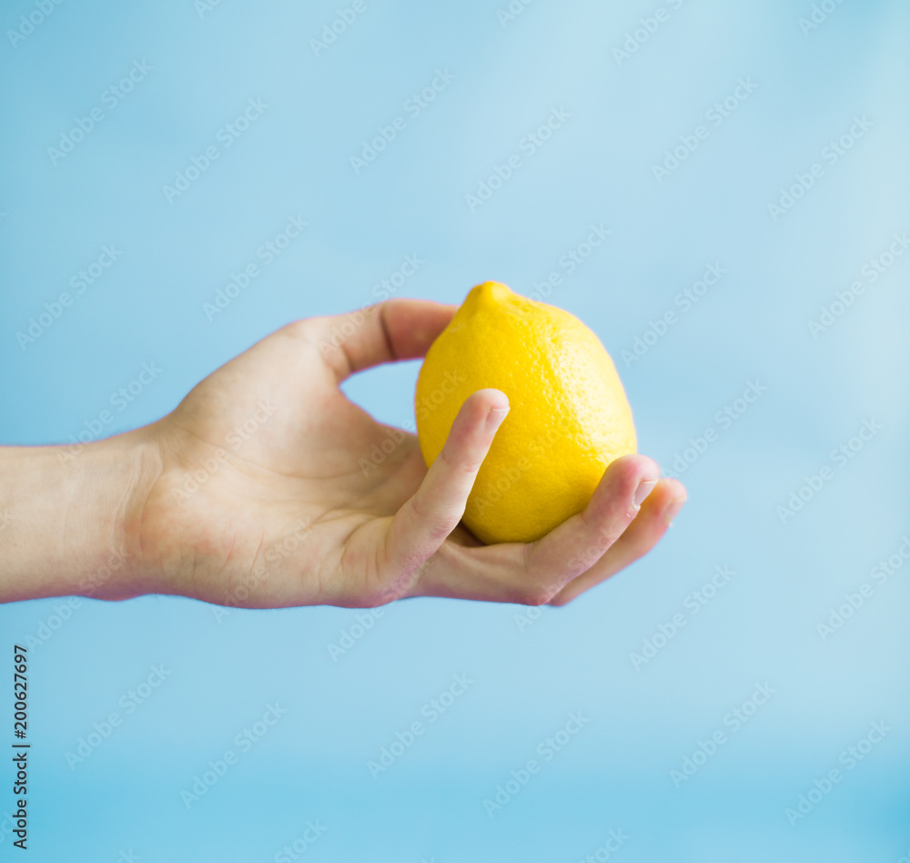 A man is holding a lemon against a blue background A man is holding a lemon against a blue background