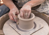 The hands of a potter creating a pot on a throwing wheel