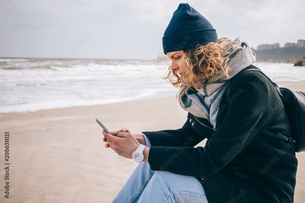 Young woman traveler with curly hair sitting on a beach