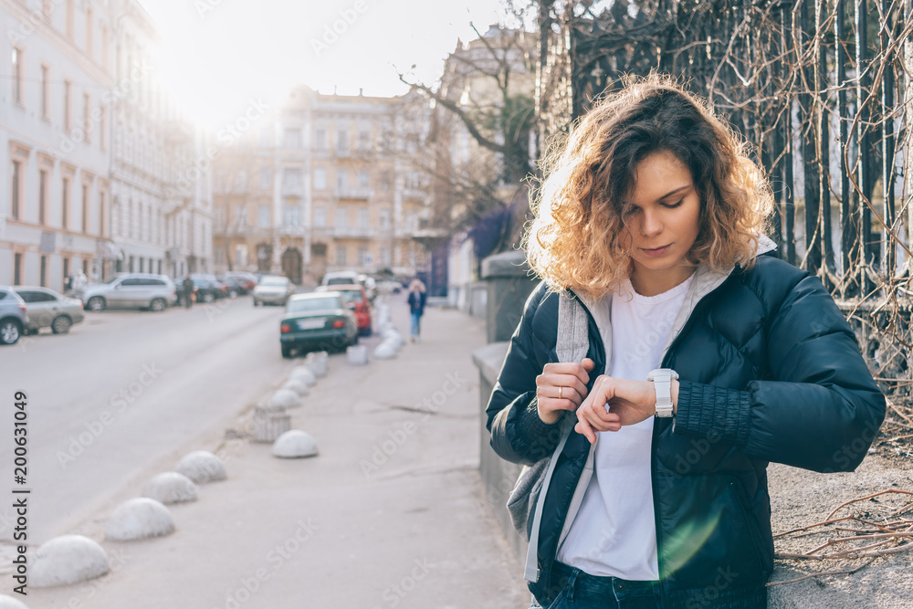 Fototapeta premium Young woman waits meeting and checks time