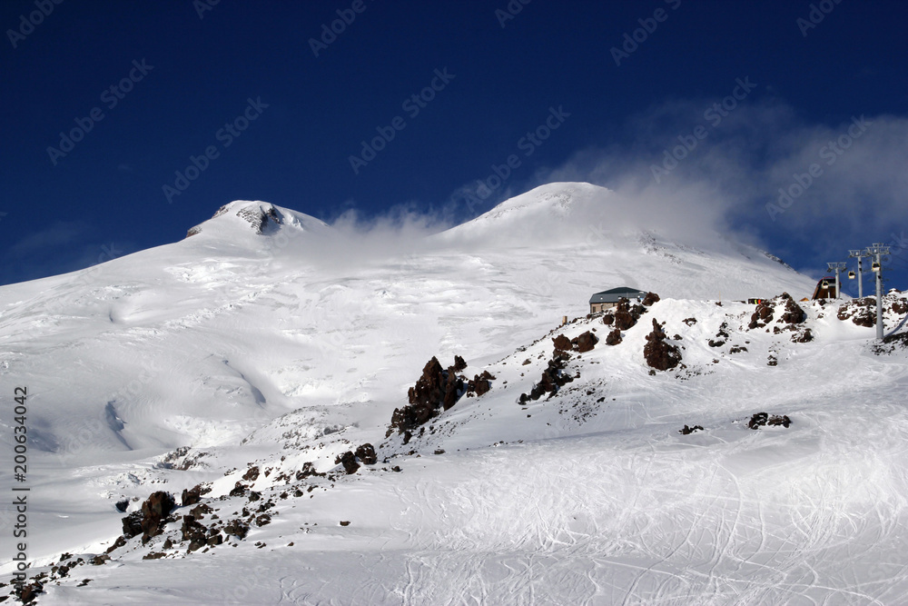 high mountains off-piste slopes for freeride with traces of skis and snowboards, sunny winter day, Caucasus Mountains, Elbrus, Russia