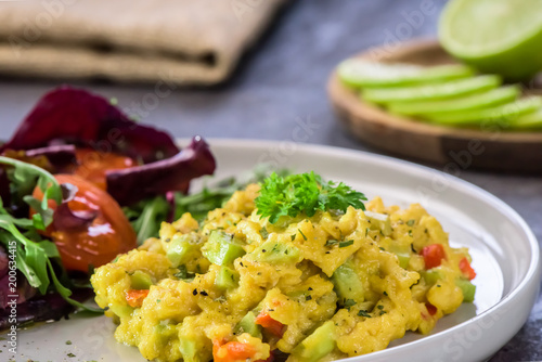 Scrambled eggs with pepper, avocado and parsley with saladdade witch eco spinach and rucola - close up.