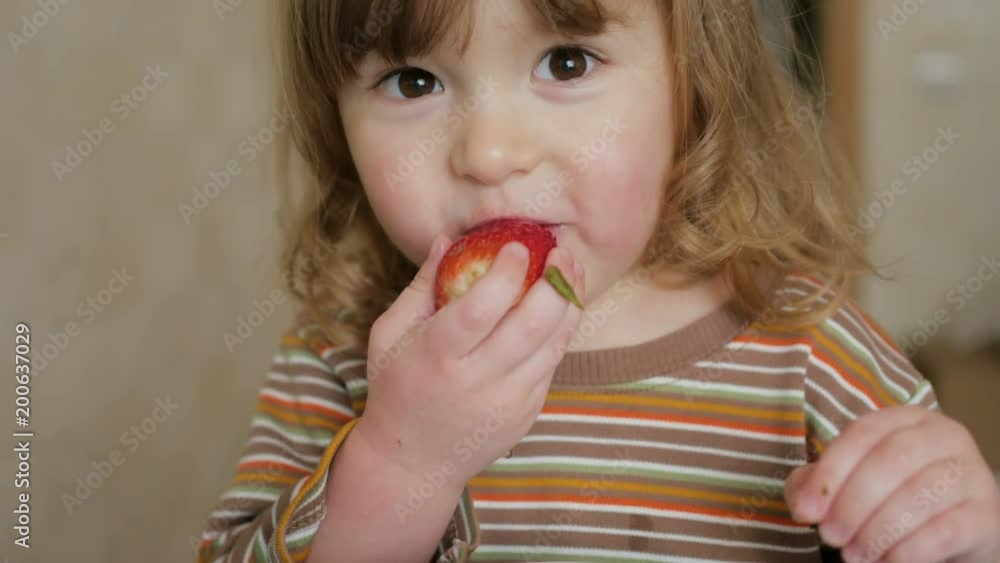Happy child little girl drinks eats strawberries in the summer home kitchen. Happy child little girl drinks eats strawberries in the summer home kitchen.