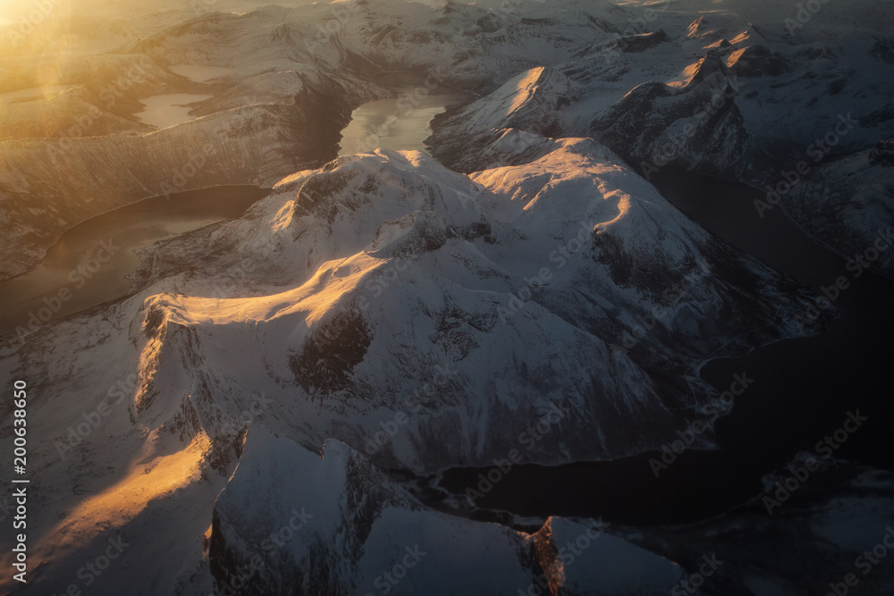 Amazing view of Norway Fjords from plane. Peaks illuminated by sun at sunrise.