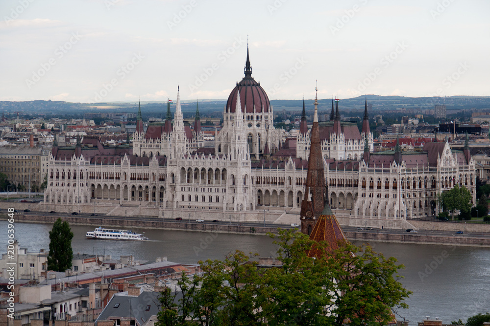 The Hungarian Parliament building in cloud weather with river Danube and ship