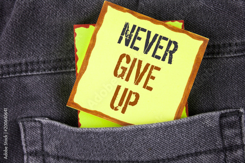 Handwriting text writing Never Give Up. Concept meaning Be persistent motivate yourself succeed never look back written on Sticky Note Paper placed on the Jeans background.