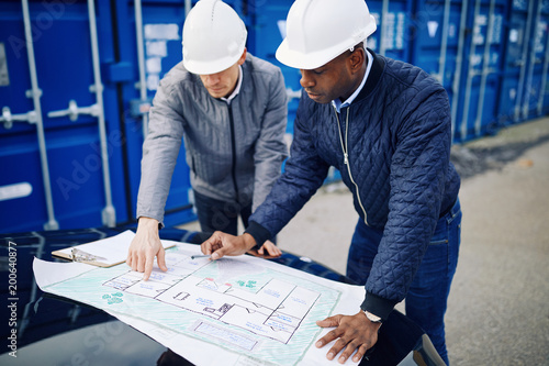 Two engineers discussing blueprints together in a shipping yard