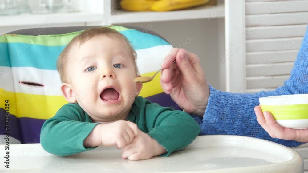 mother feeding little baby with puree and spoon mother feeding little baby with puree and spoon