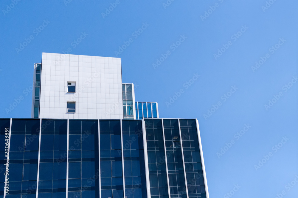 Modern office buildings with blue windows against clean blue sky.