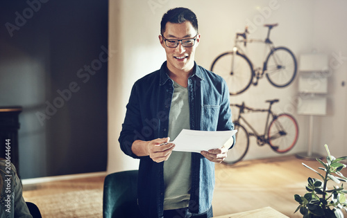 Smiling Asian man standing in an office giving a presentation