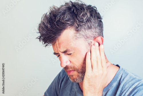Man with earache is holding his aching ear body pain concept photo