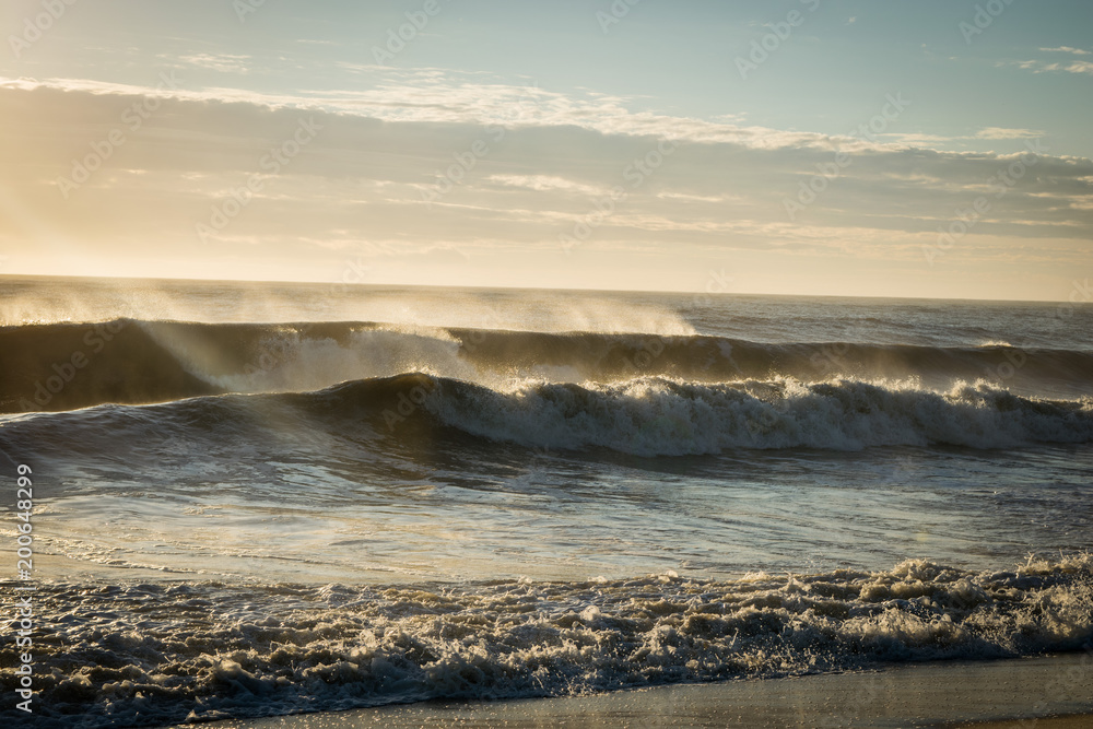 Waves breaking on the shore at sunrise.