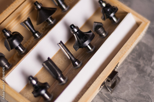 Set of steel router bit for milling cutter in rectangle wooden box with metal lock on old broken worn gray concrete floor