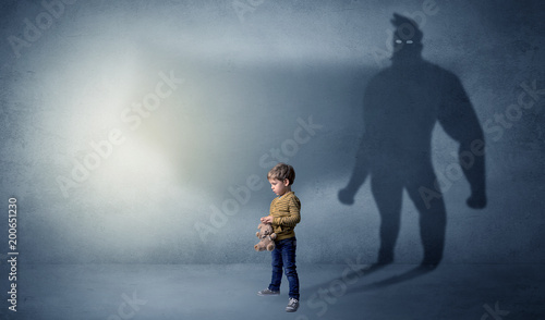 Cute kid in a room with plush on his hand and hero shadow on his background   © ra2 studio