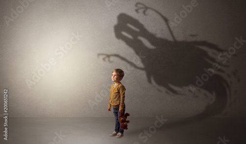 Scary ghost shadow in a dark empty room with a cute blond child 