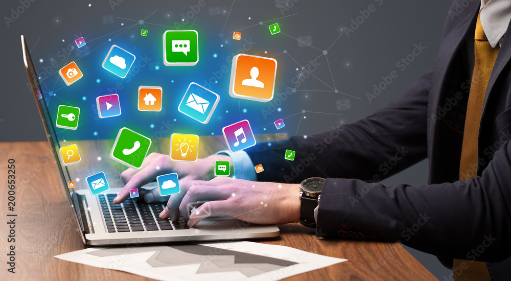 Businessman hand typing on laptop with flying application icons around
Businessman hand typing on laptop with flying application icons around