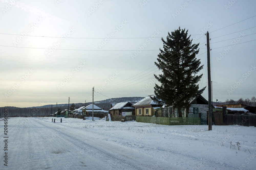 Roadside small Siberian village, in the evening in the winter season.