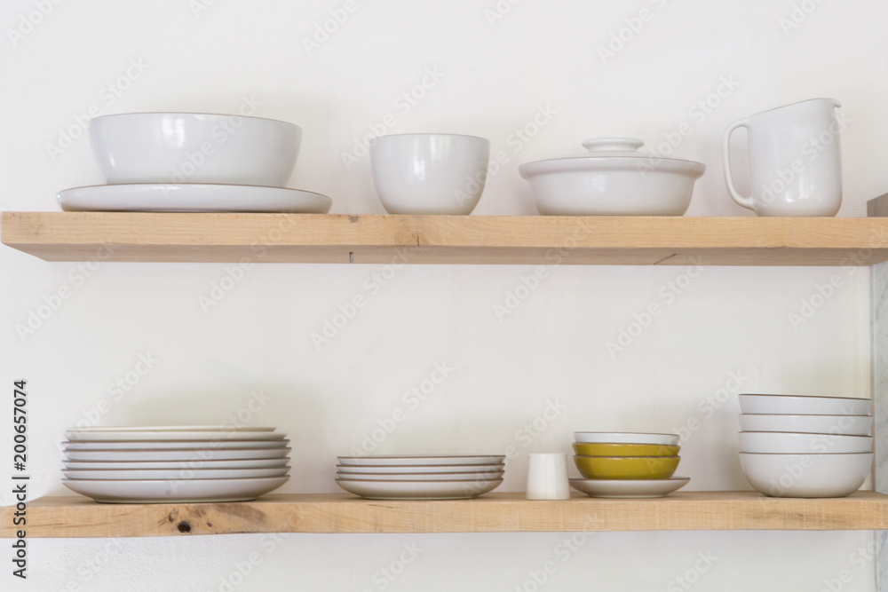 Various ceramic crockery arranged on wooden shelf Various ceramic crockery arranged on wooden shelf