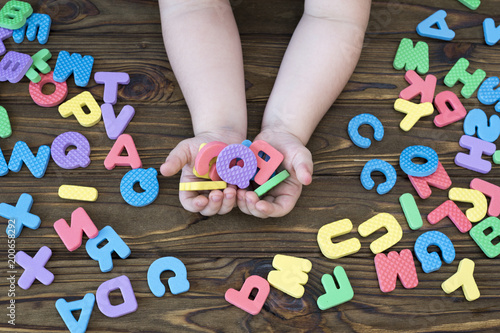 letters of the English alphabet in the hands of a child on a wooden background. education. a game.