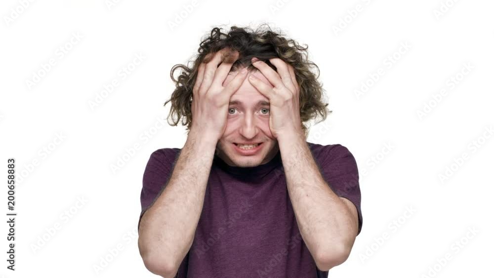 Portrait of angry tense man 20s grabbing his head and screaming, while gesturing in annoyance, over white background. Concept of emotions Portrait of angry tense man 20s grabbing his head and screaming, while gesturing in annoyance, over white background. Concept of emotions