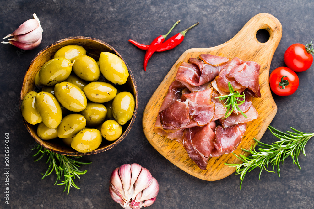 Fototapeta premium Prosciutto with rosemary on a black background.