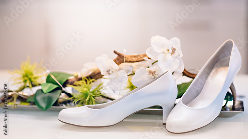White bride shoes near a vase with white orchids