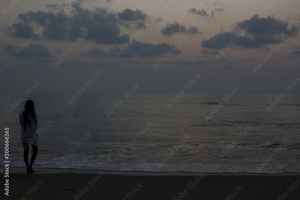 View of woman standing on the beach at dawn with copy space.