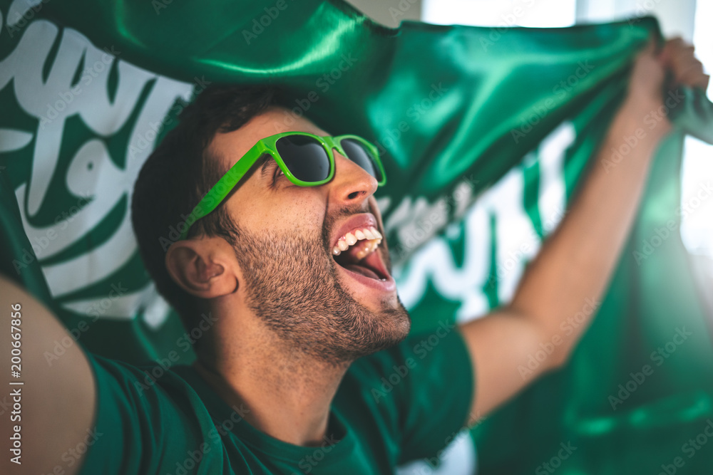 Naklejka premium Saudi Arabia fan celebrating with flag