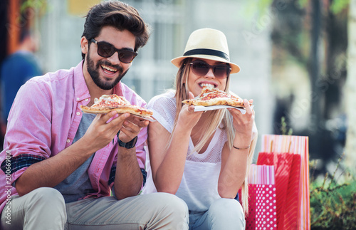 Couple eating pizza outdoors. Dating, consumerism, food, lifestyle concept