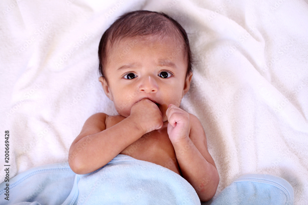 Playful newborn baby lying down in bed Playful newborn baby lying down in bed