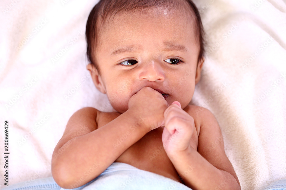 Playful newborn baby lying down in bed Playful newborn baby lying down in bed