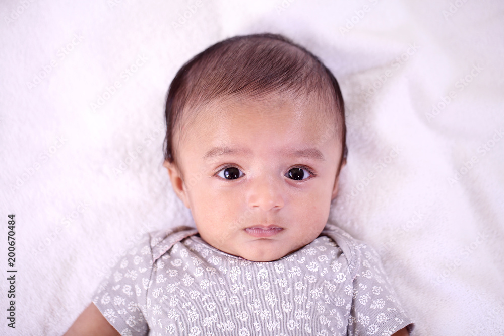 Playful newborn baby lying down in bed