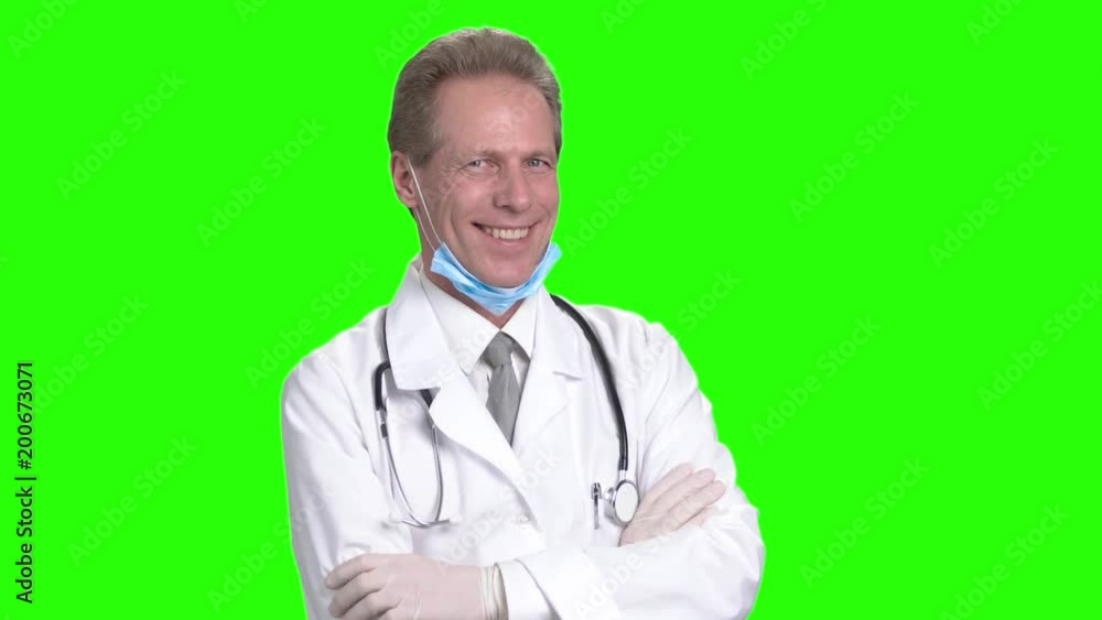 Positive friendly mature doctor with crossing arms. Happy doctor with medical coat and stethoscope, green hromakey background. Positive friendly mature doctor with crossing arms. Happy doctor with medical coat and stethoscope, green hromakey background.