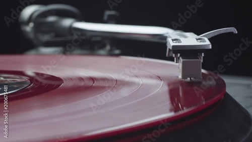 Pressing play and turning on the vintage turntable player with red vinyl