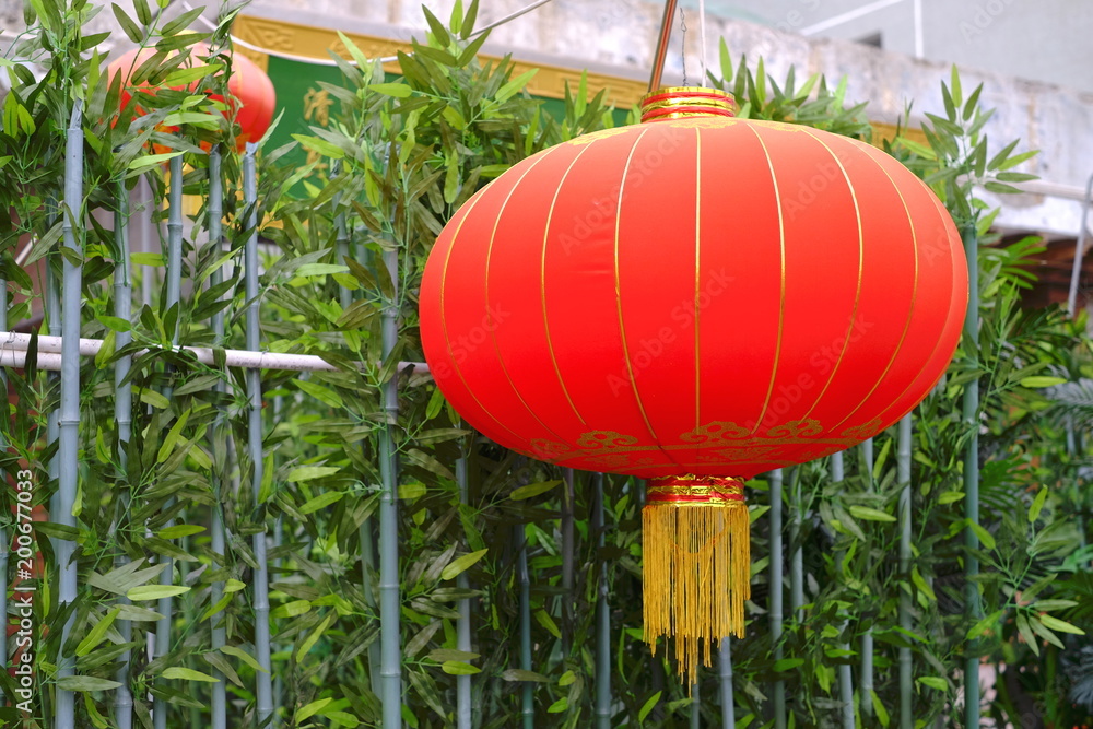 Obraz premium Traditional chinese lantern hanging on green hedge, red and golden colors