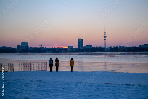 winter landscape in Hamburg, Germany; people enjouing sunset on the coast photo